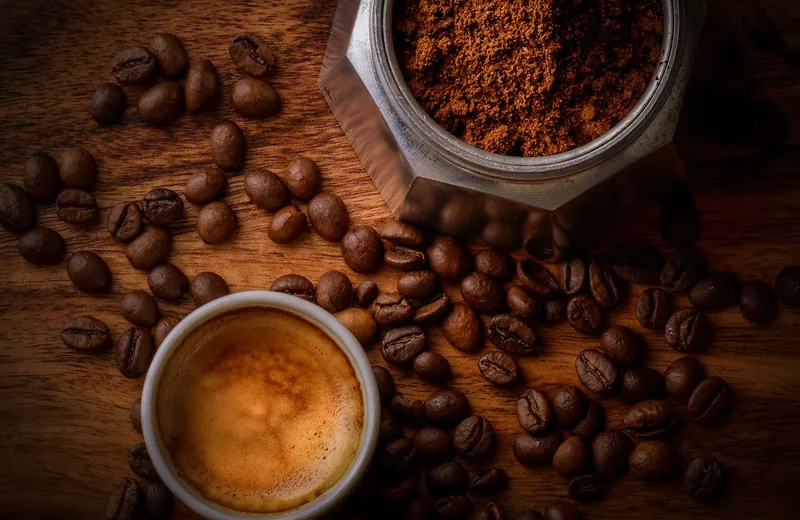 Coffee beans beside a prepared cup